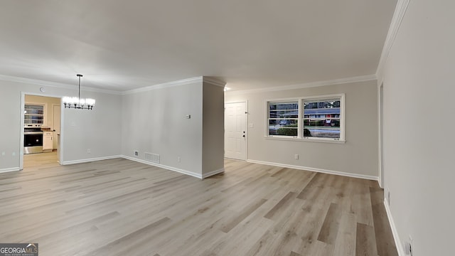 unfurnished room with light hardwood / wood-style floors, crown molding, and an inviting chandelier