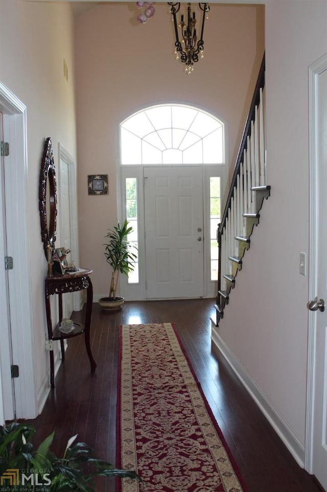 foyer featuring a towering ceiling, dark hardwood / wood-style flooring, and a healthy amount of sunlight