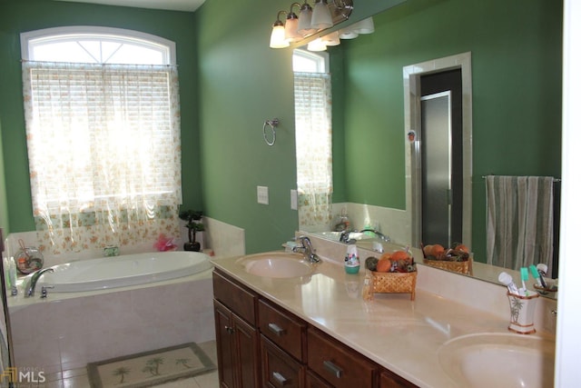 bathroom with vanity, a relaxing tiled tub, tile patterned floors, and a healthy amount of sunlight