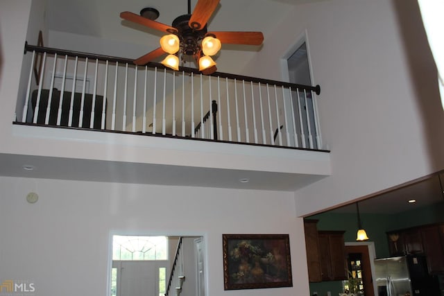 stairs with ceiling fan and a towering ceiling