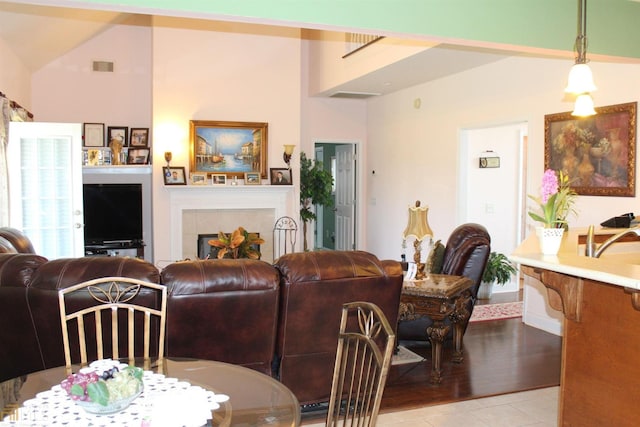 living room with vaulted ceiling, light tile patterned floors, and a tiled fireplace