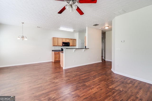 unfurnished living room with ceiling fan with notable chandelier, a textured ceiling, and dark hardwood / wood-style flooring