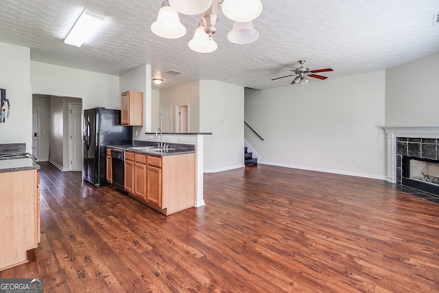 kitchen with a textured ceiling, sink, a tiled fireplace, and ceiling fan with notable chandelier