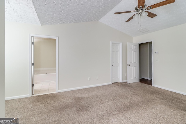 unfurnished bedroom with ensuite bathroom, a textured ceiling, ceiling fan, and carpet flooring