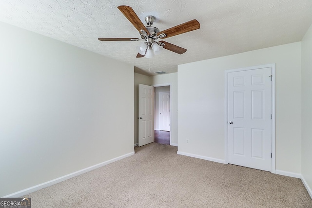 unfurnished bedroom with a textured ceiling, ceiling fan, and carpet