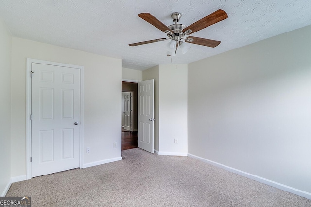 unfurnished bedroom with ceiling fan, light carpet, and a textured ceiling