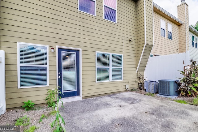 view of exterior entry with a patio area and central AC unit