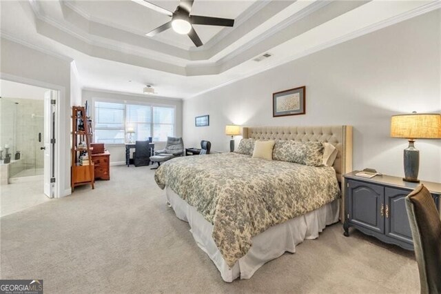 carpeted bedroom with a raised ceiling, ensuite bath, ceiling fan, and crown molding