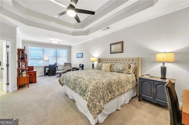 carpeted bedroom featuring a raised ceiling, connected bathroom, ceiling fan, and ornamental molding