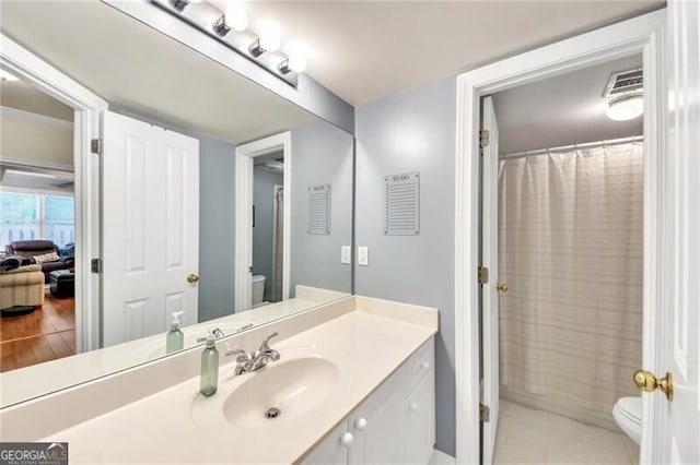 bathroom with tile patterned flooring, vanity, toilet, and curtained shower