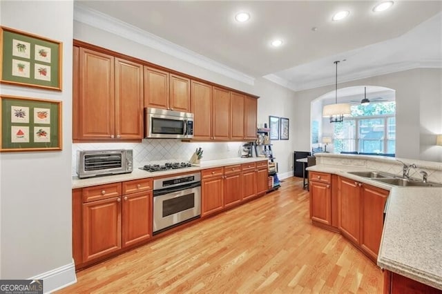 kitchen with sink, hanging light fixtures, light wood-type flooring, stainless steel appliances, and a chandelier