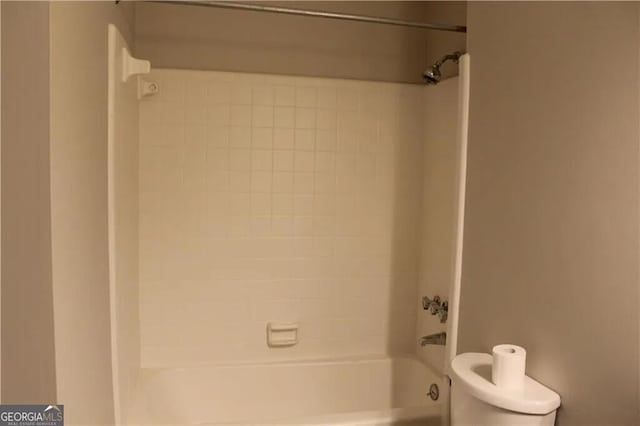 bathroom with tiled shower / bath combo and toilet