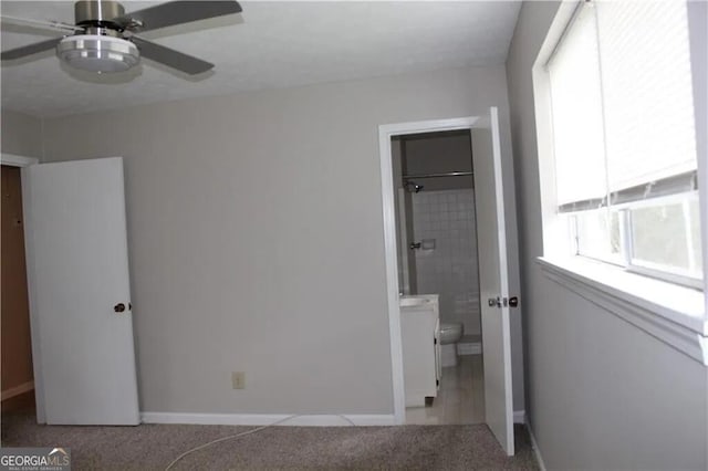 unfurnished bedroom with ceiling fan, light colored carpet, and ensuite bathroom