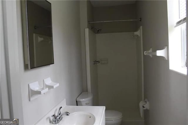 bathroom with toilet, a shower, and vanity