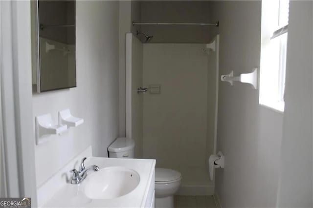 bathroom featuring tile patterned floors, toilet, vanity, and walk in shower