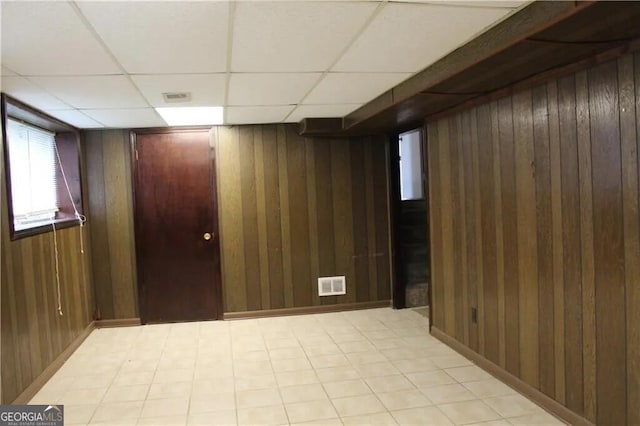 basement with wooden walls and a drop ceiling