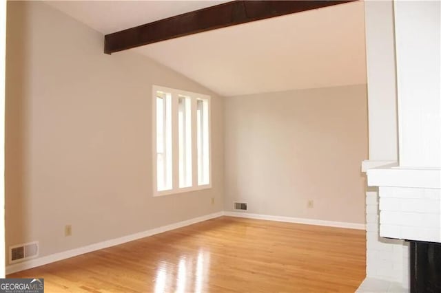 unfurnished living room featuring a fireplace, lofted ceiling with beams, and light hardwood / wood-style flooring