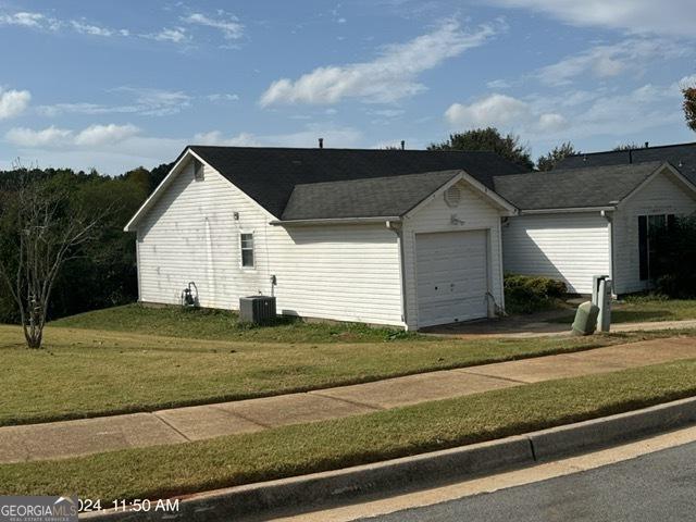 view of property exterior with central AC, a garage, and a lawn