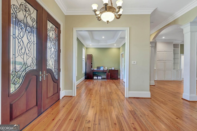 entrance foyer with light hardwood / wood-style flooring, an inviting chandelier, decorative columns, and crown molding