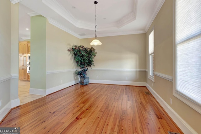 unfurnished dining area featuring light hardwood / wood-style flooring, crown molding, and a tray ceiling