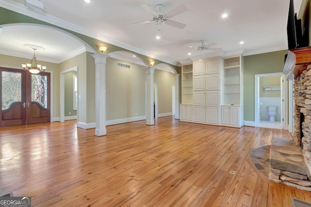 unfurnished living room with french doors, ornate columns, ornamental molding, light hardwood / wood-style flooring, and a fireplace