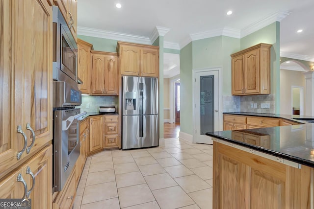 kitchen with ornamental molding, backsplash, appliances with stainless steel finishes, and dark stone counters