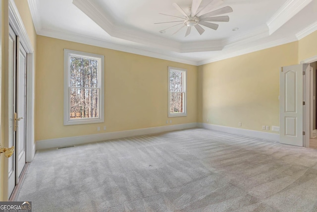 spare room with ceiling fan, a raised ceiling, ornamental molding, and light carpet