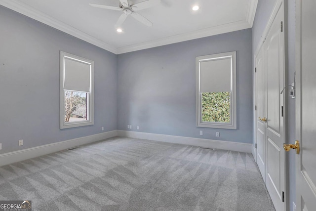 carpeted spare room with ceiling fan and ornamental molding