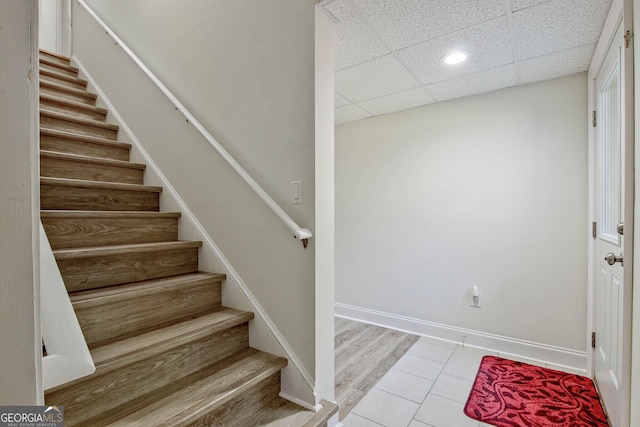 stairs with tile patterned flooring and a paneled ceiling