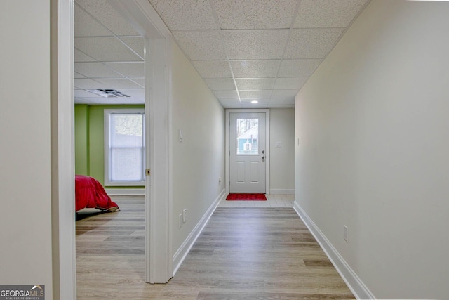 doorway featuring light wood-type flooring, a drop ceiling, and a healthy amount of sunlight