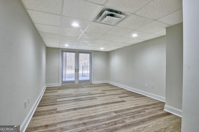 unfurnished room with french doors, light hardwood / wood-style floors, and a drop ceiling