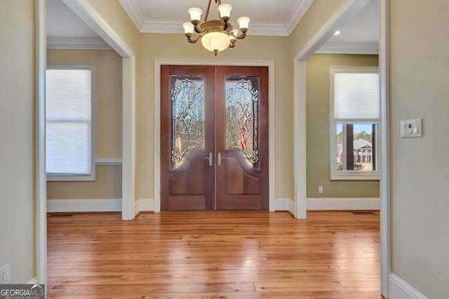 entrance foyer featuring a notable chandelier, plenty of natural light, and ornamental molding