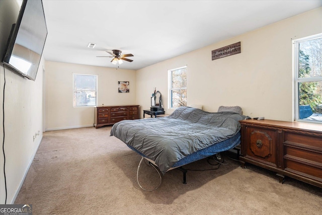 bedroom with multiple windows, light carpet, and ceiling fan