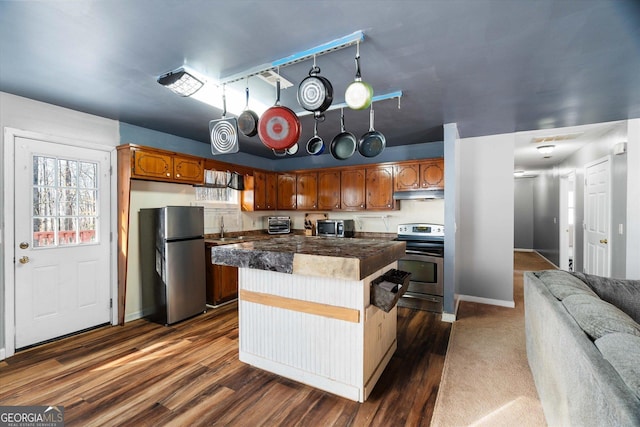 kitchen featuring a center island, sink, stainless steel appliances, dark hardwood / wood-style floors, and a breakfast bar