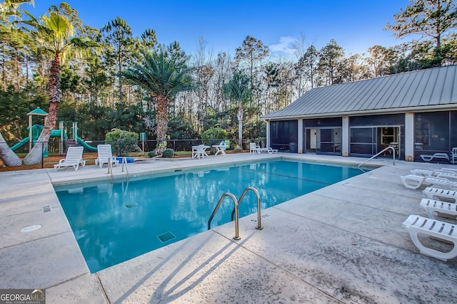 view of swimming pool with a playground, a patio area, and a sunroom