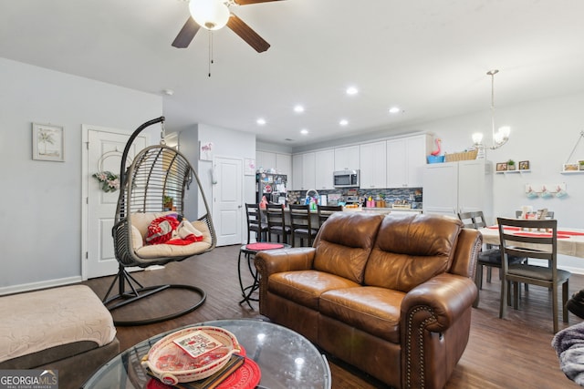 living room with dark hardwood / wood-style flooring and ceiling fan with notable chandelier