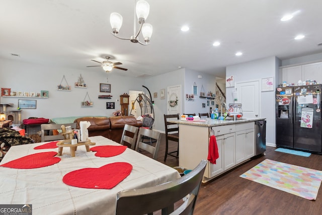 dining area with ceiling fan with notable chandelier, dark wood-type flooring, and sink