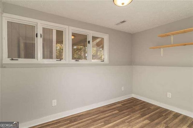 empty room with a textured ceiling and dark wood-type flooring