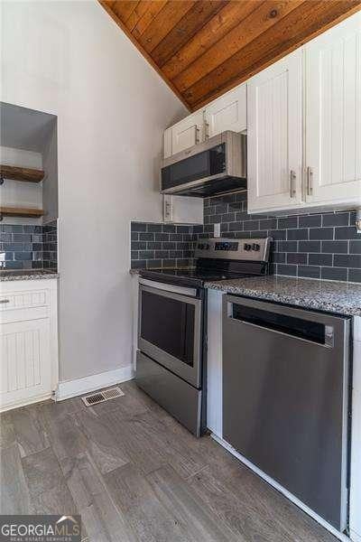 kitchen featuring lofted ceiling, dark hardwood / wood-style flooring, white cabinetry, stainless steel appliances, and wood ceiling