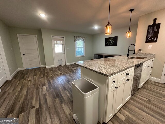 kitchen with kitchen peninsula, light stone counters, stainless steel dishwasher, sink, and white cabinetry