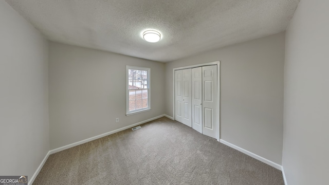 unfurnished bedroom with carpet flooring, a textured ceiling, and a closet