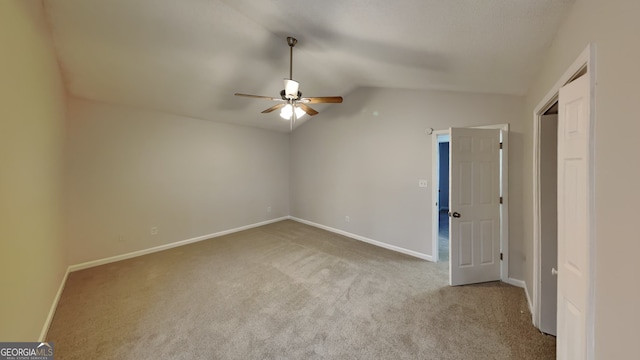 empty room with light colored carpet, vaulted ceiling, and ceiling fan