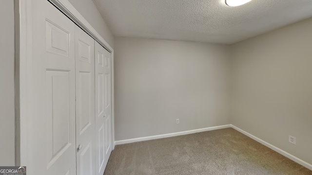 unfurnished bedroom featuring a textured ceiling, carpet floors, and a closet