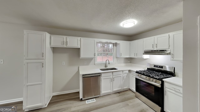 kitchen featuring white cabinetry, sink, light wood-type flooring, and appliances with stainless steel finishes