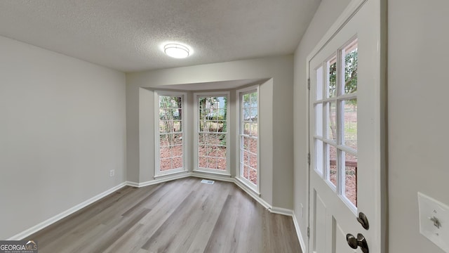 empty room featuring light wood-type flooring and a textured ceiling