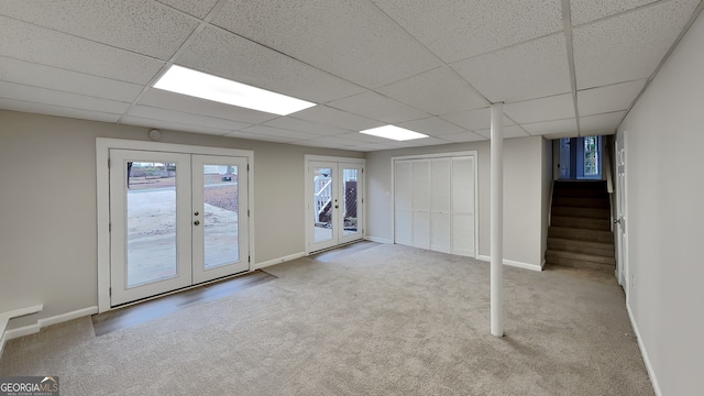 basement with light carpet, french doors, and a drop ceiling