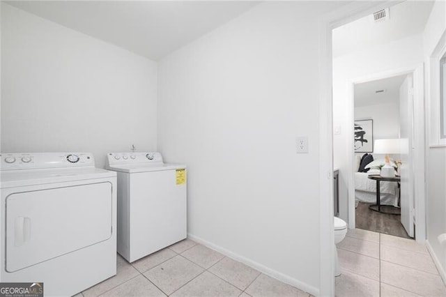 laundry room with washer and clothes dryer and light tile patterned floors