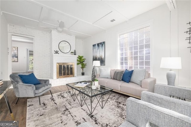 living room with a brick fireplace, coffered ceiling, brick wall, ceiling fan, and wood-type flooring