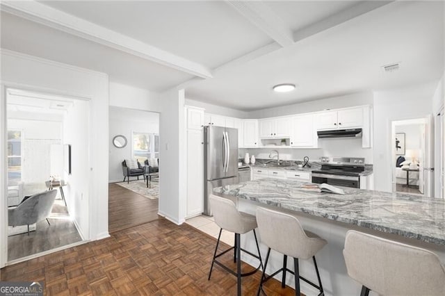 kitchen featuring light stone counters, stainless steel appliances, sink, beamed ceiling, and white cabinetry