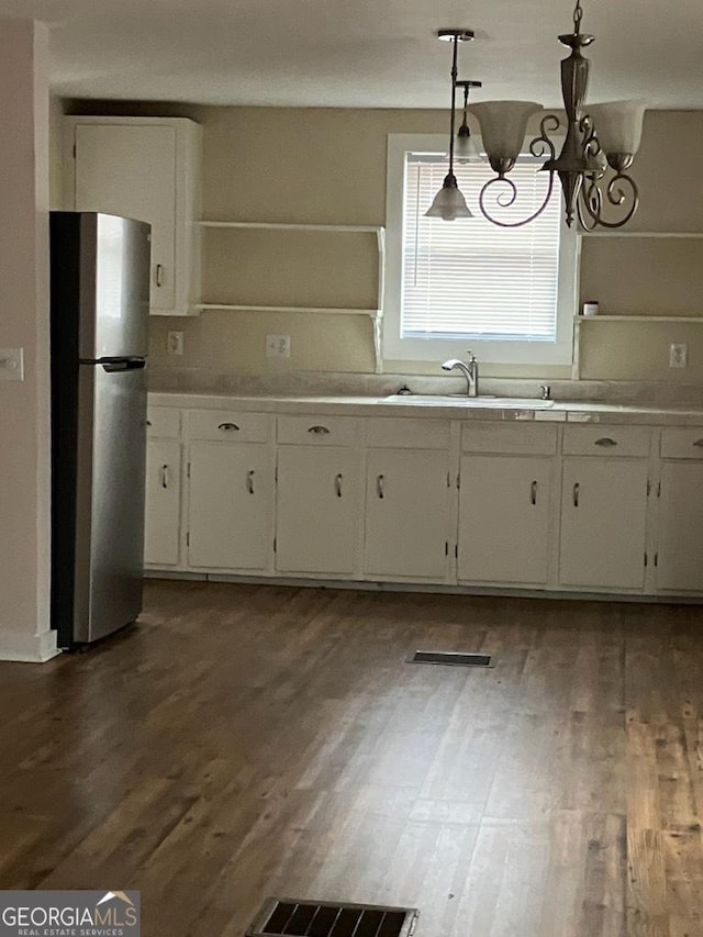 kitchen with sink, pendant lighting, an inviting chandelier, white cabinets, and stainless steel refrigerator